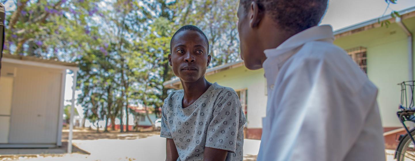 Un conseiller en observance du traitement contre le VIH s'entretient avec un adolescent en traitement à l'extérieur de l'hôpital du district de Makhumbe, au Zimbabwe.
