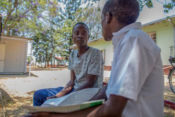 HIV treatment adherence counsellor speaks to an adolescent treatment buddy outdoors at Makhumbe District Hospital in Zimbabwe.