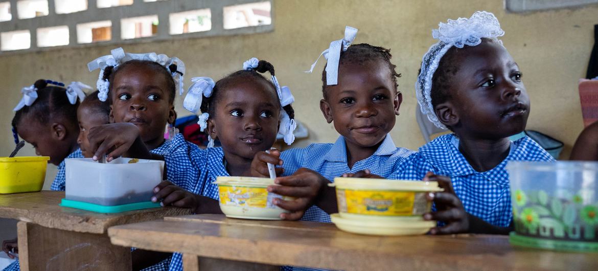 En Haïti, des enfants mangent un repas chaud fourni par l'ONU et ses partenaires à l'école.