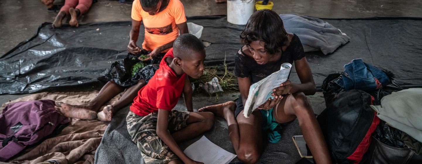 A mother helps her child to study at the Delmas 4 Olympique Boxing Arena where they are now sheltering.