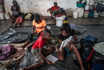 हेती में अपने घर से विस्थापित हुए लोगों ने एक बॉक्सिंग परिसर में शरण ली है, जहाँ एक माँ अपने बच्चे को पढ़ा रही है.