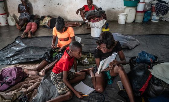 हेती में अपने घर से विस्थापित हुए लोगों ने एक बॉक्सिंग परिसर में शरण ली है, जहाँ एक माँ अपने बच्चे को पढ़ा रही है.