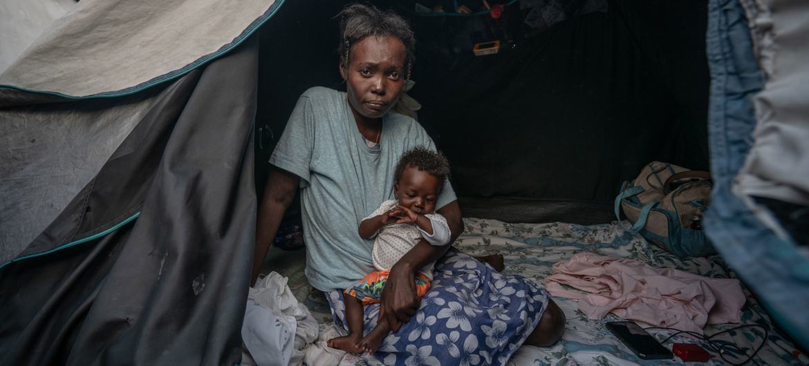 Una mujer con su hijo, quien nació en un campamento para familias desplazadas por la violencia en Puerto Príncipe, improvisado en las instalaciones de una escuela..