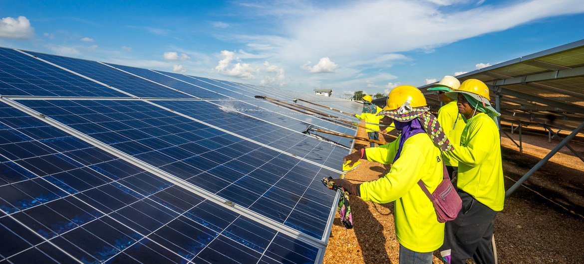 Maintenance crew clean solar panels to ensure maximum electricity generation at a solar farm in Thailand.