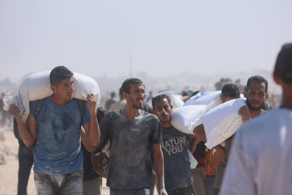 Des habitants de Gaza transportent de la farine après une livraison d'aide.