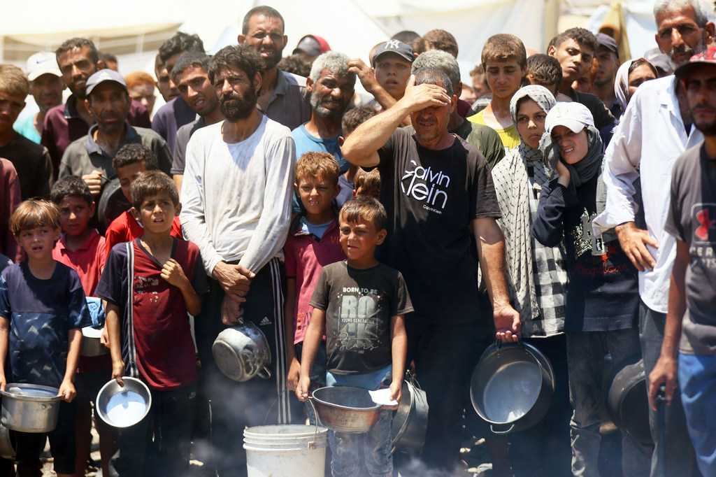 Gente buscando comida en una cocina comunitaria de la ciudad de Gaza.
