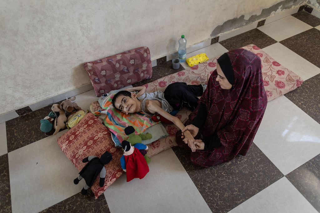 Un jeune homme de 20 ans souffrant de malnutrition sévère et de paralysie cérébrale reçoit l'attention d'une femme.