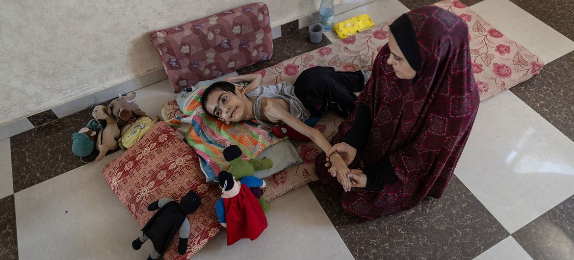 Un joven de 20 años, gravemente desnutrido y con parálisis cerebral, recibe atención de una mujer.