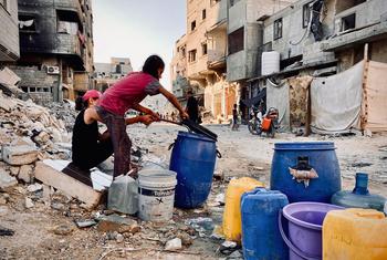 Children collect water in Gaza.