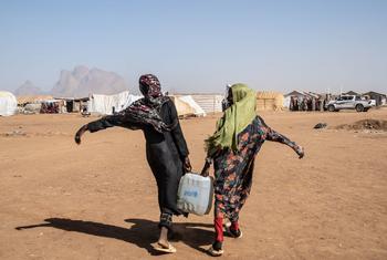 Duas mulheres carregam água em campos de refugiados