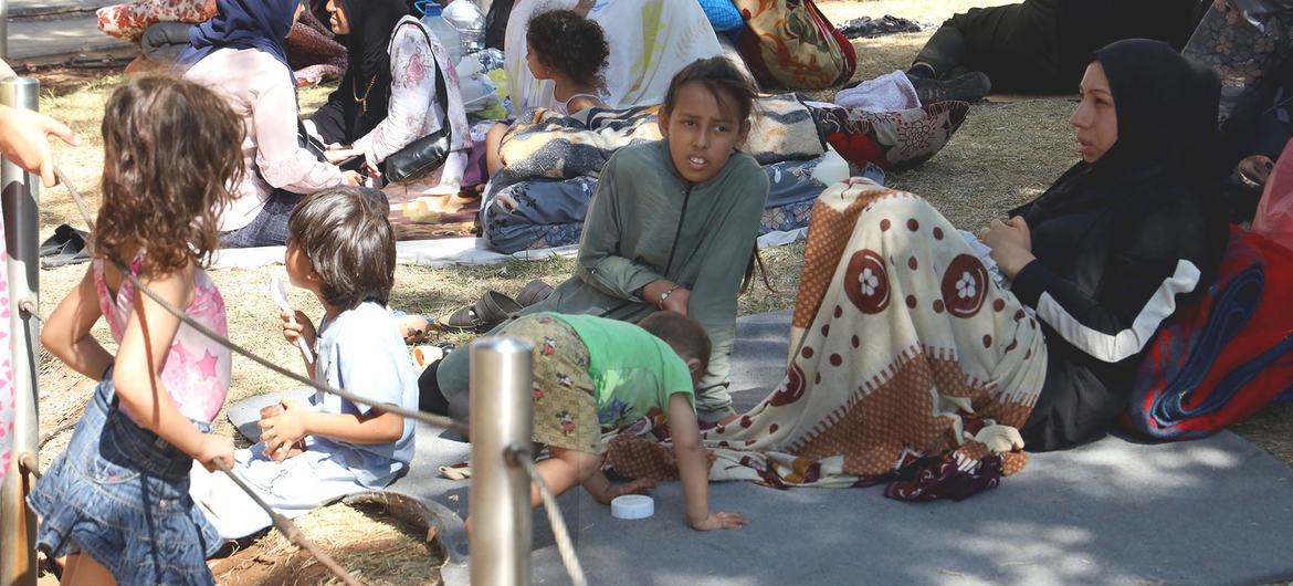 Members of a family who fled their home in Lebanon rest under a tree.