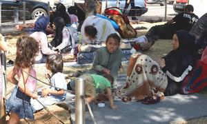 Members of a family who fled their home in Lebanon rest under a tree.