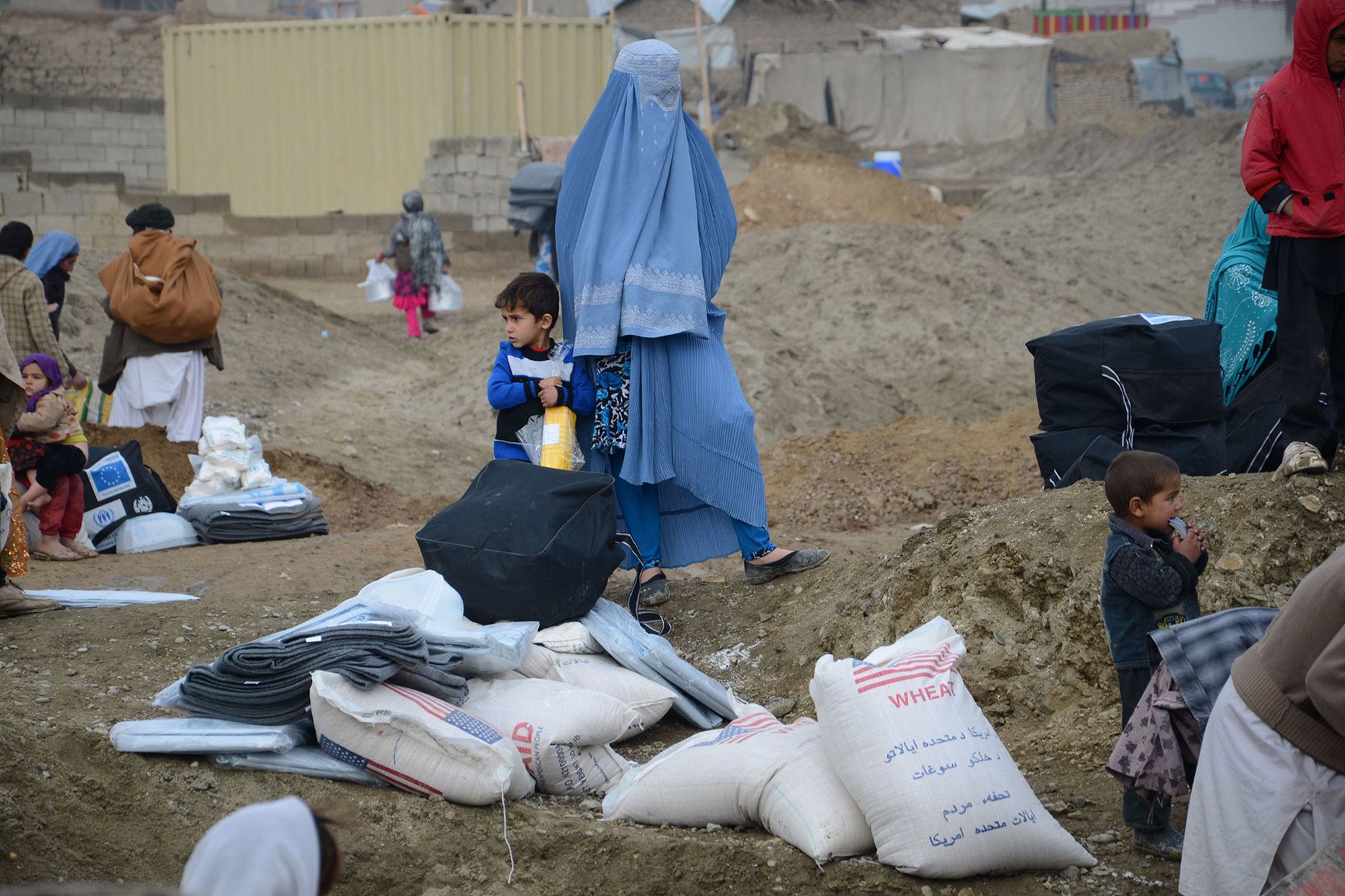 امرأة وطفلها يسيران في مخيم للنازحين في أفغانستان.