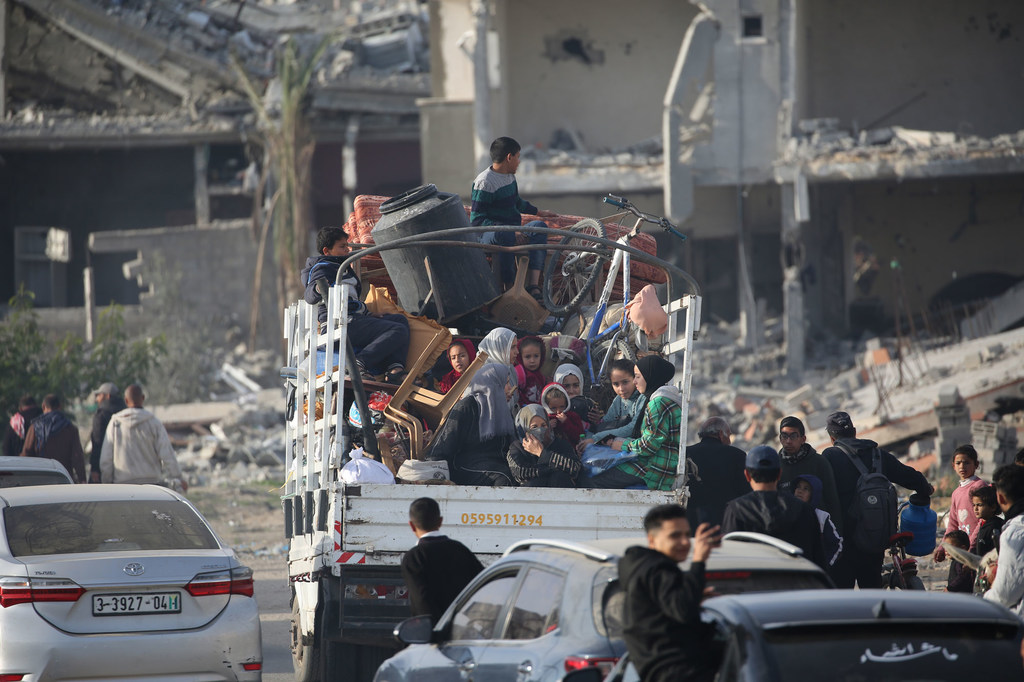 Displaced Palestinians carry their belongings as they head back to Rafah, in the southern Gaza Strip, following the ceasefire...