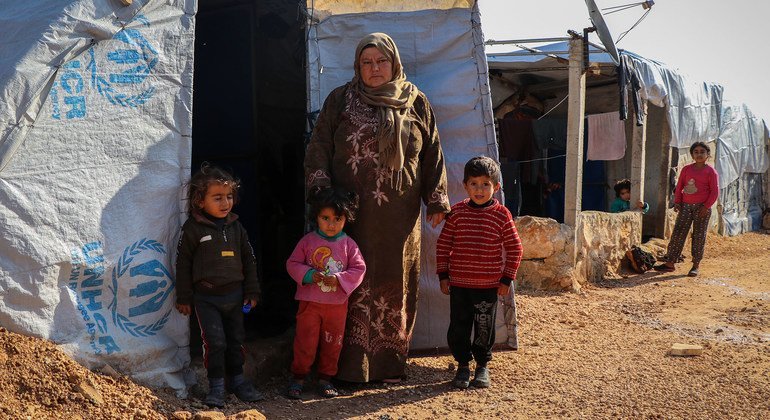 أسرة نازحة تقف أمام خيمتها في أحد المخيمات الواقعة في ريف حلب الشمالي بسوريا.