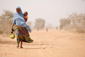 امرأة تحمل طفلها في أرض قاحلة في منطقة الساحل