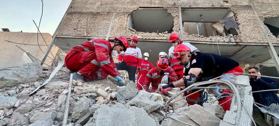 Voluntarios de la Sociedad de la Media Luna Roja de Irán buscan entre los escombros de un edificio dañado en Minab, Irán.
