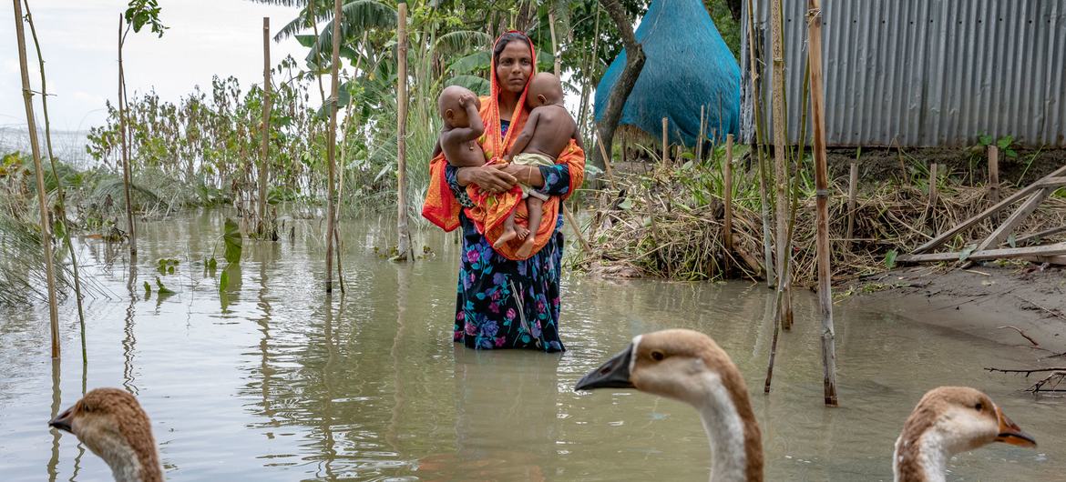 Una madre lleva a sus hijas a través de las aguas de una inundación durante la estación monzónica de julio en Bangladesh.