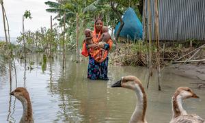 A mother carries her daughters through flood waters during July's monsoon season in Bangladesh.