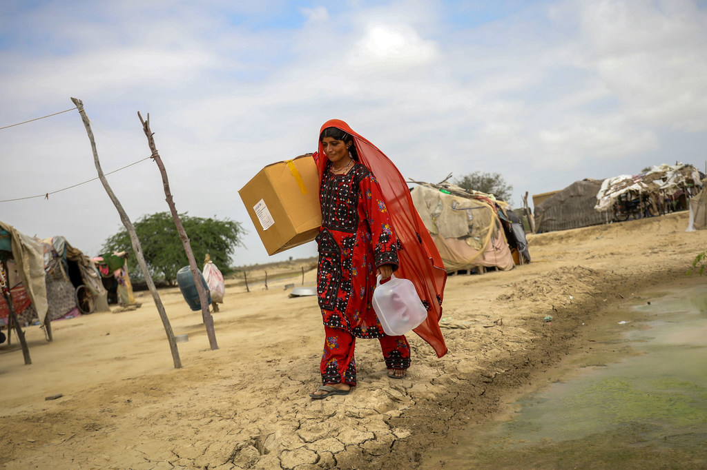 Une femme transporte des articles d'aide humanitaire vers son village dans la province du Baloutchistan, au Pakistan.
