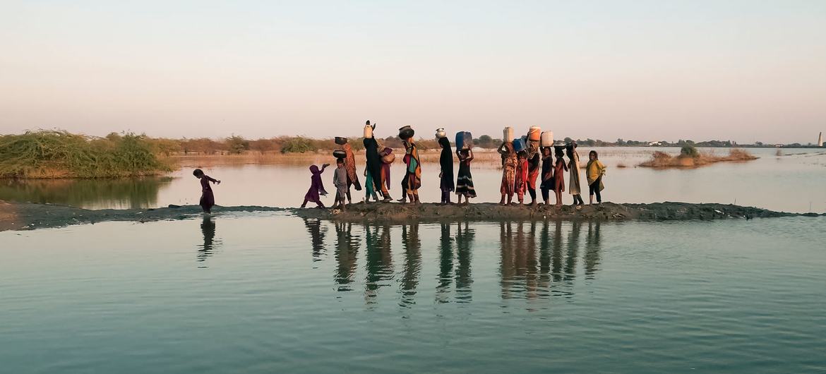 Mujeres y niñas recogen agua tras las inundaciones en la provincia meridional paquistaní de Sindh.