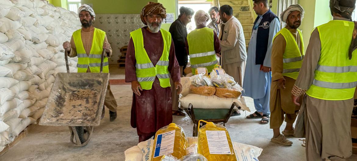 واسکٹ اور پگڑیوں میں ملبوس مرد افغانستان میں ورلڈ فوڈ پروگرام کے گودام میں گندم، تیل اور دال پر مشتمل کھانے کے پارسل تقسیم کر رہے ہیں۔