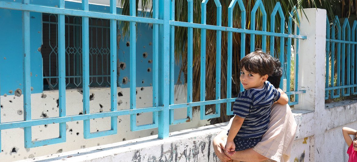 一名巴勒斯坦男子在2021年5月被轰炸的加沙达拉吉的一家诊所前抱着他的儿子。