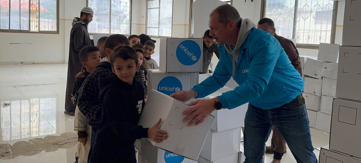 Сотрудник ЮНИСЕФ 15 декабря 2025 года вручает ребенку на мероприятии по распространению зимней одежды в городе Газа.