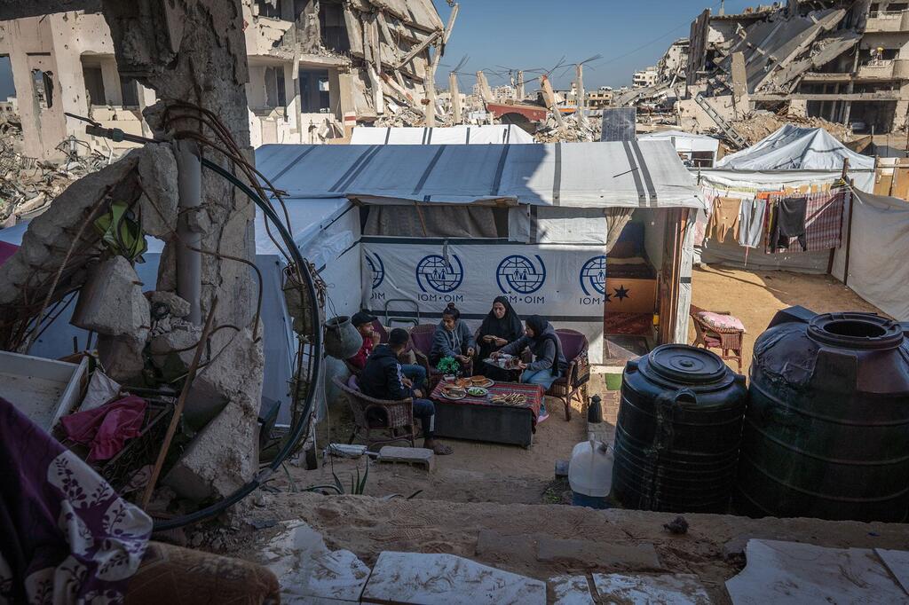 一个巴勒斯坦家庭在加沙的一个临时避难所共享一顿饭,