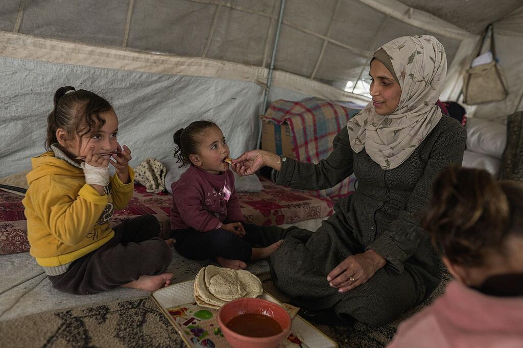 A mother in Gaza cares for her children in a temporary shelter.