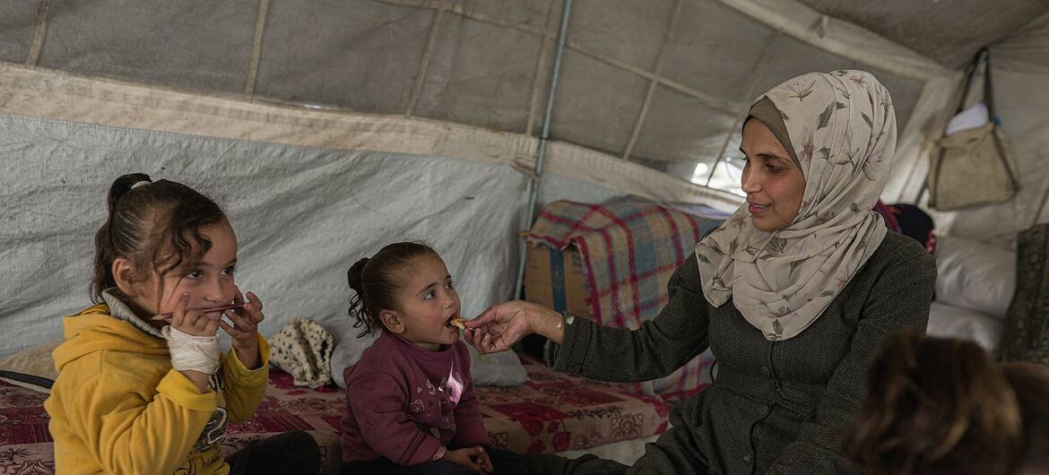 A resilient mother in Gaza, Jehan, feeds her daughters in a tent, highlighting the critical role of WFP nutrition assistance in their recovery from severe malnutrition after losing her family in war.