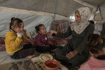 A resilient mother in Gaza, Jehan, feeds her daughters in a tent, highlighting the critical role of WFP nutrition assistance in their recovery from severe malnutrition after losing her family in war.