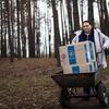 Uma mulher empurra uma carruagem carregada com caixas de ajuda alimentar do Programa Mundial de Alimentos através de uma floresta na Ucrânia, destacando os esforços humanitários em andamento nas zonas de conflito.