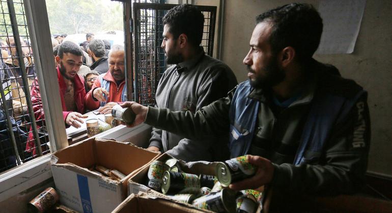 Los palestinos esperan en largas colas en una escuela de la UNRWA convertida en refugio mientras se distribuyen alimentos.
