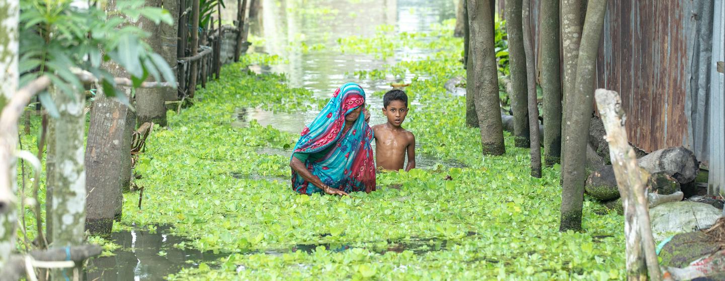 Une femme et un enfant pataugent dans les eaux de crue à Kurigram, au Bangladesh.