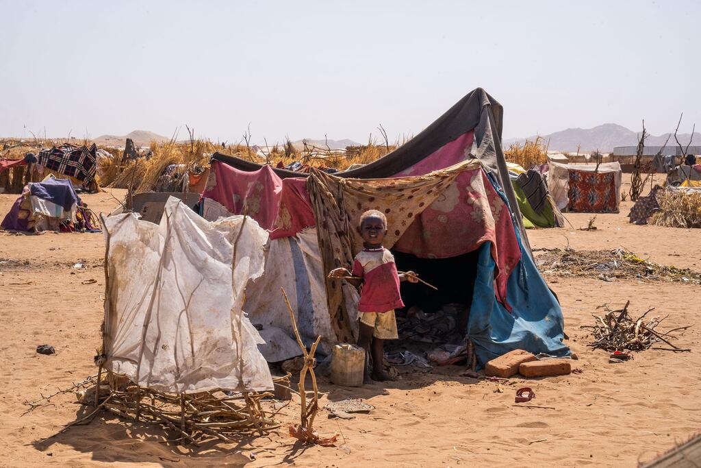A child stands in front of a makeshift tent in a refugee camp in Tawila, North Darfur, following displacement due to ongoing conflict.