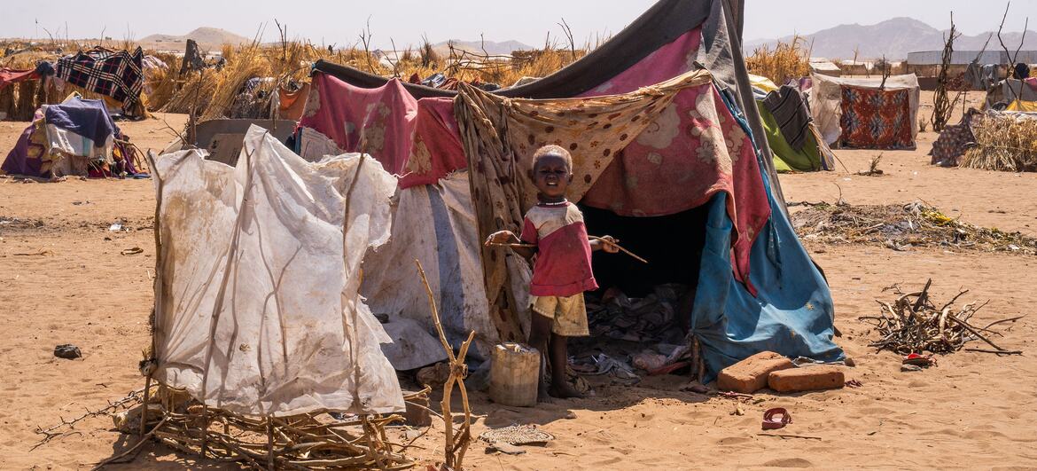 A young child stands in front of a makeshift tent in a desert refugee camp in Tawila, North Darfur, Sudan, following displacement due to ongoing conflict. UNICEF and partners are providing emergency assistance.