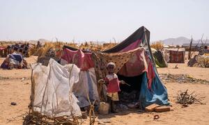 A young child stands in front of a makeshift tent in a desert refugee camp in Tawila, North Darfur, Sudan, following displacement due to ongoing conflict. UNICEF and partners are providing emergency assistance.