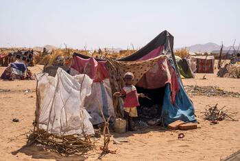 A young child stands in front of a makeshift tent in a desert refugee camp in Tawila, North Darfur, Sudan, following displacement due to ongoing conflict. UNICEF and partners are providing emergency assistance.