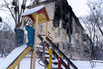 یوکرین کے شہر کیف میں اہم بنیادی ڈھانچے پر حملوں کے بعد شدید نقصان پہنچا رہائشی عمارت کے سامنے برف سے ڈھکا ہوا کھیل کا میدان کھڑا ہے۔ اس منظر میں موسم سرما کے دوران بچوں والے خاندانوں کو متاثر کرنے والے انسانی بحران پر روشنی ڈالی گئی ہے۔