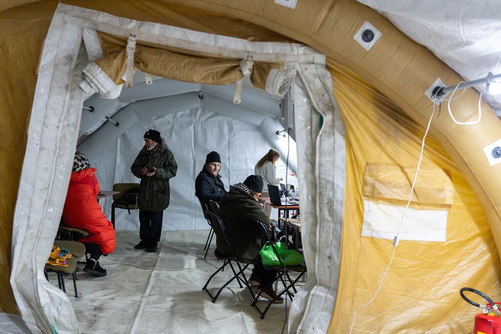 سكان يتجمعون داخل خيمة مزودة بنظام تدفئة في كييف، أوكرانيا، خلال فصل شتاء قارس شهد انقطاعا في التيار الكهربائي والتدفئة.