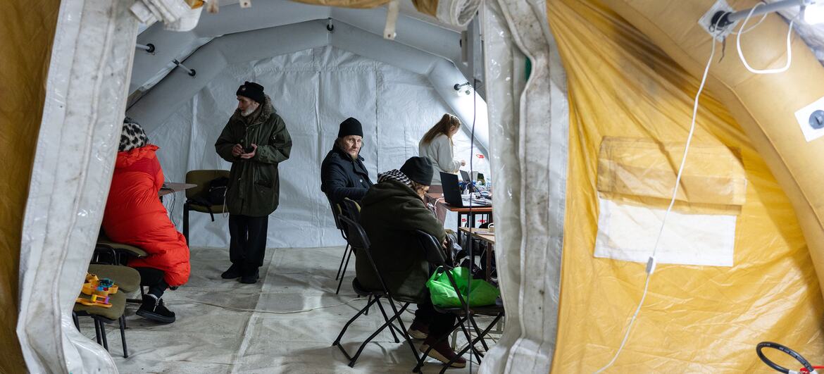 داخل خيمة حرارية ساخنة في كييف، أوكرانيا، يجلس السكان ويشحنون الأجهزة بينما يتعاملون مع درجات حرارة الشتاء الباردة في الخارج. تدعم اليونيسيف هذه النقاط بمواد نفسية اجتماعية مثل الألعاب والألعاب للأطفال.