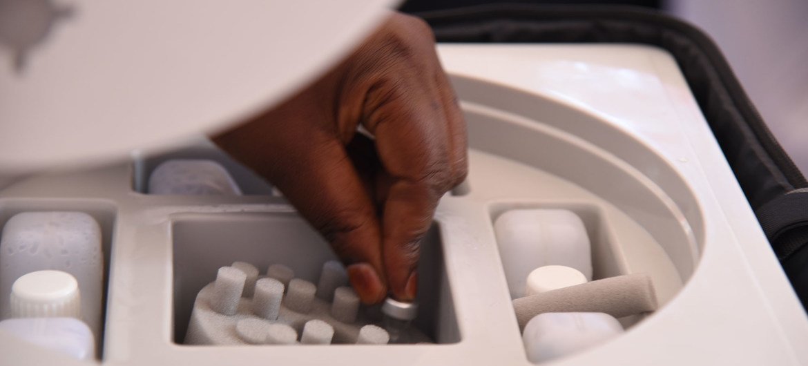 A health worker picks a vial of the AstraZeneca COVID-19 vaccine from a cooler box in Uganda.