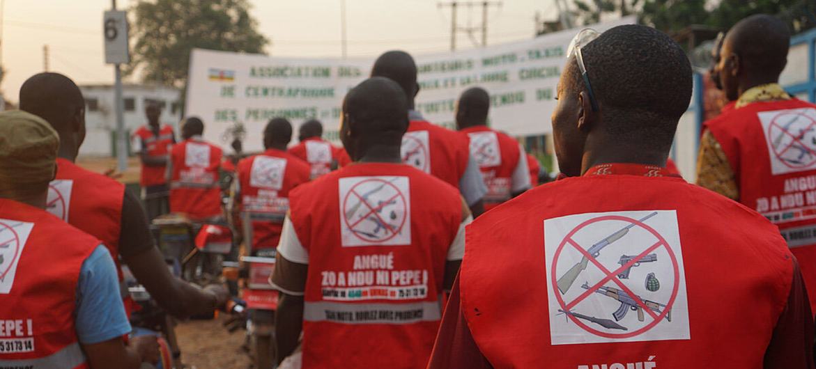 Un grupo de hombres africanos en motocicletas visten chalecos rojos con un símbolo que prohíbe las armas pequeñas y ligeras, como parte de una campaña de concienciación en Bangui, República Centroafricana.