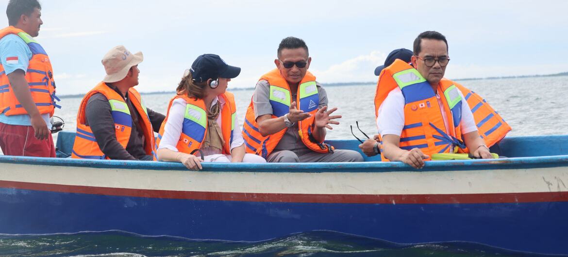 Indonesian diplomat Tri Tharyat sits in a boat with other officials wearing life jackets on the water.