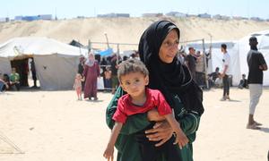 A mother holds her child in a camp for displaced people in Gaza. 