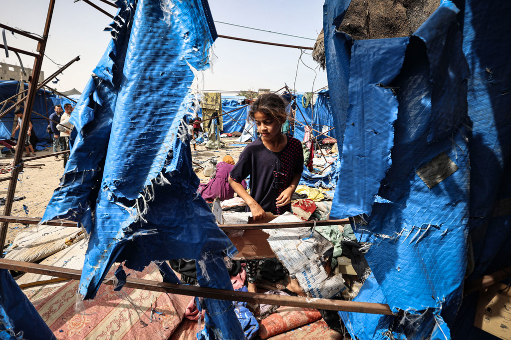 Uma jovem visita sua tenda que foi destruída após ataques aéreos em Deir al-Balah, Gaza
