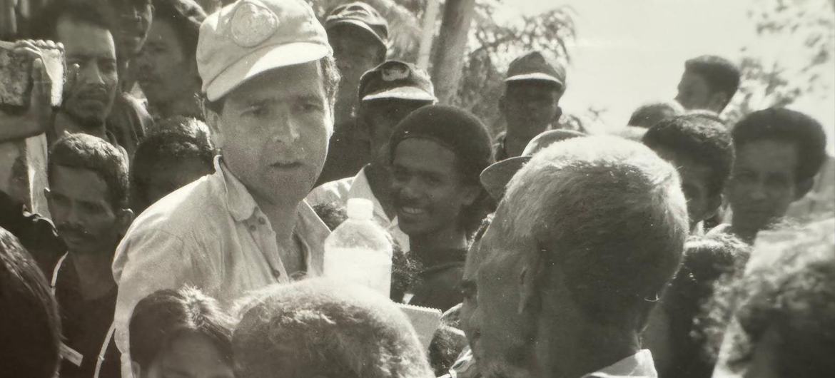 Un miembro del personal de la ONU apoya a los votantes mientras emiten su sufragio en un caótico centro de votación.