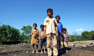 Une famille se tient devant les ruines de sa maison qui a été incendiée pendant une période de troubles civils.