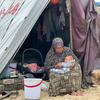 Uma mulher cuida de um bebê do lado de fora de uma tenda em Gaza.